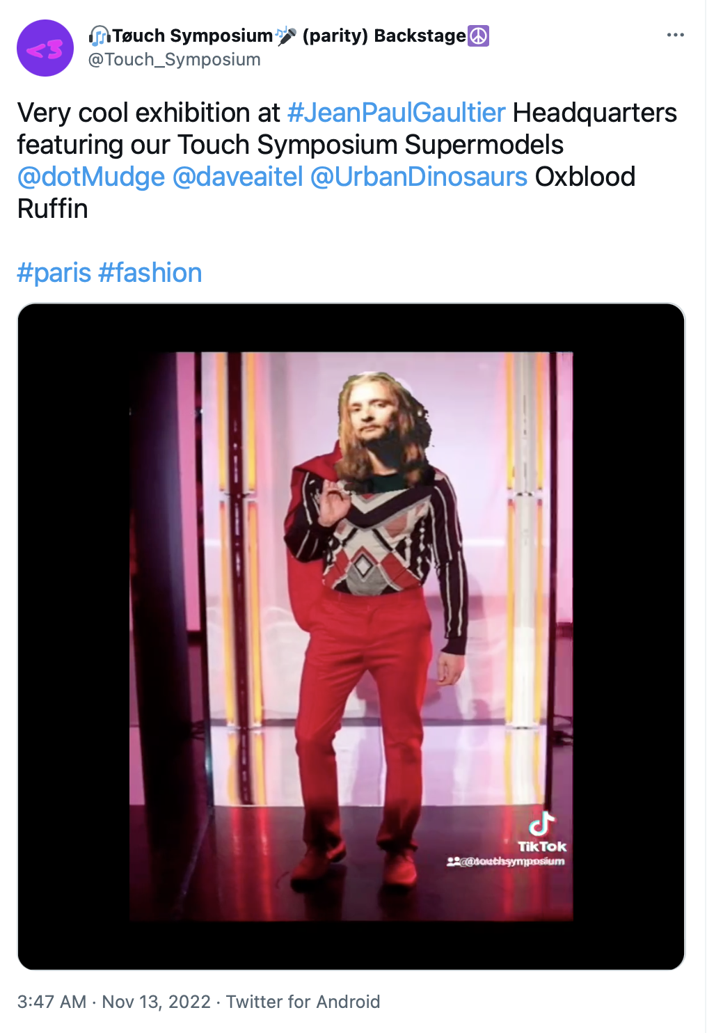 13 Nov 2022 tweet from @Touch_Symposium: A professionally-taken full-length photo of a male fashion model, but superimposed over the model's head is a crudely cut-and-pasted picture of Mudge's head. The text reads: 'Very cool exhibition at #JeanPaulGaultier Headquarters featuring our Touch Symposium Supermodels @dotMudge @daveaitel @UrbanDinosaurs Oxblood Ruffin #paris #fashion'